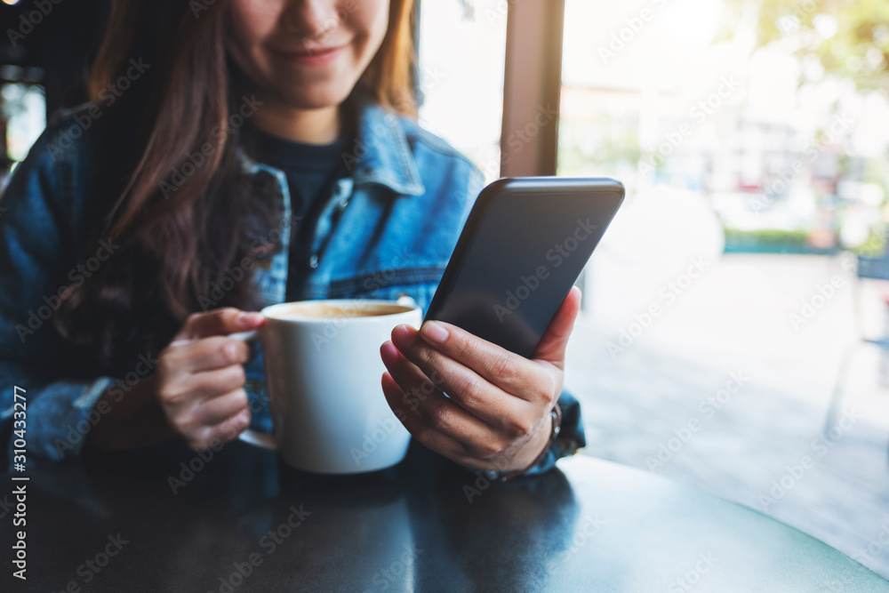 Closeup image of a woman holding and using mobile phone while drinking coffee Closeup image of a woman holding and using mobile phone while drinking coffee