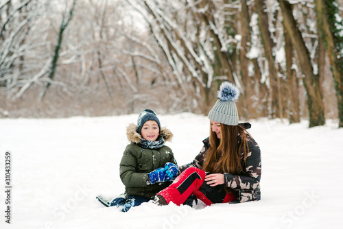 Happy christmas vacation. Young mother and son having fun in winter park. Family playing with snow outdoors