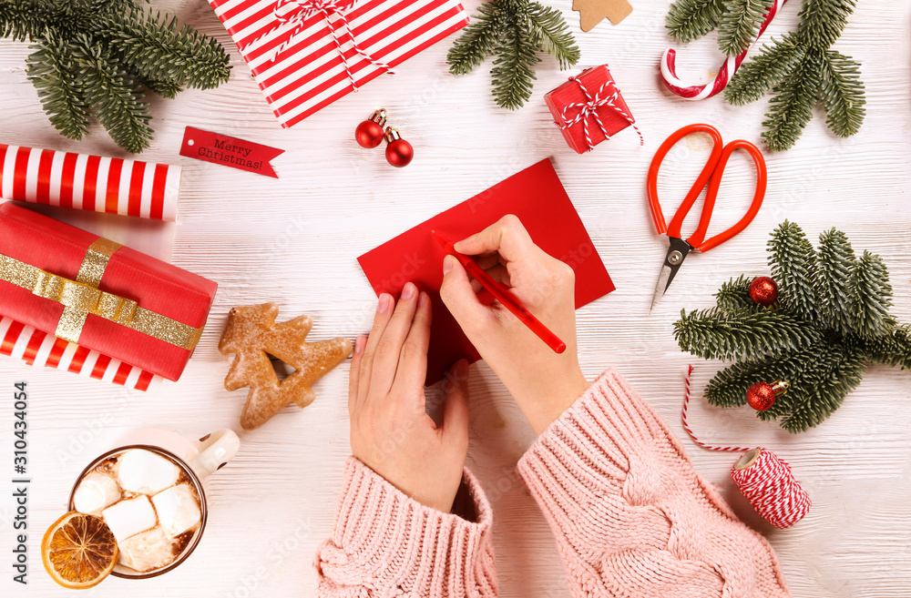 Top view of woman wearing knitted sweater getting ready for winter holiday season, wrapping presents and preparing decorations on wooden table. Background, copy space, flat lay,