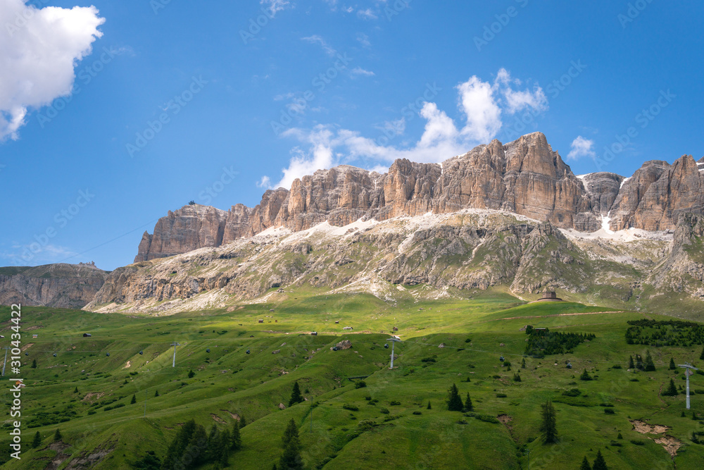 Panoramic view on the Sella massif and Piz Boe. Dolomites, Italy, Beautiful sunny summer day, green hills blue sky Passo Pordoi