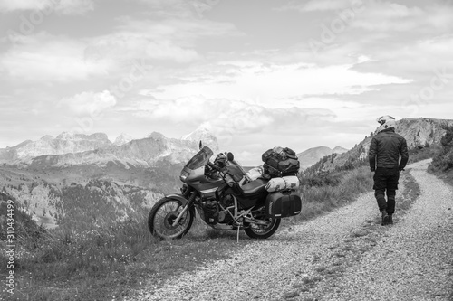 Motorcycle rider enjoy the momment. Touring adventure motorbike on the top of mountain, enduro, off road, beautiful view, black and white, freedom, extreme vacation. Copy space. Passo Pordoi, Italy photo