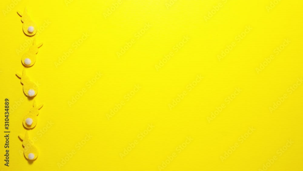 Yellow velvet bunnies on yellow background on the left with space for text. Stop motion animation flat lay top view Yellow velvet bunnies on yellow background on the left with space for text. Stop motion animation flat lay top view