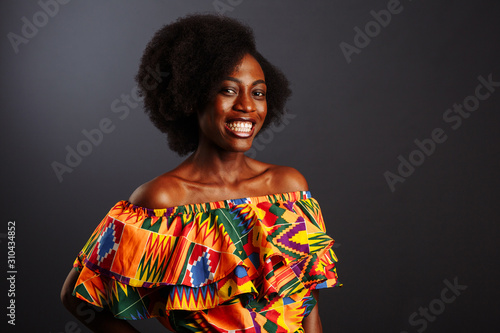 Young African woman from Ivory Coast in traditional clothes posing and smiling at camera