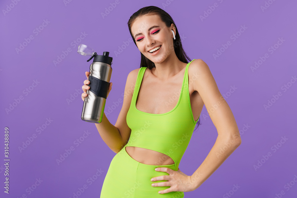 Photo of nice laughing woman using earpods and holding water bottle Photo of nice laughing woman using earpods and holding water bottle