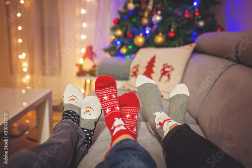 Four pair of feet in Christmas socks, mom and children lying on the couch, enjoying christmas time © Tomsickova