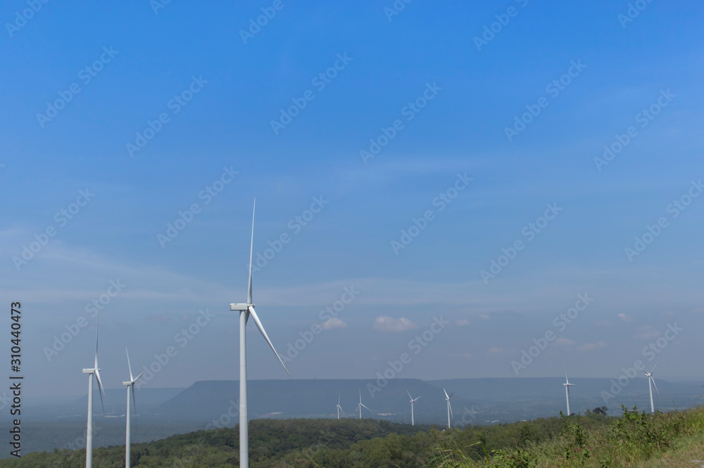 Mountain wind turbines for generating electricity Behind the mountains in the sky, there are white clouds on a sunny day.