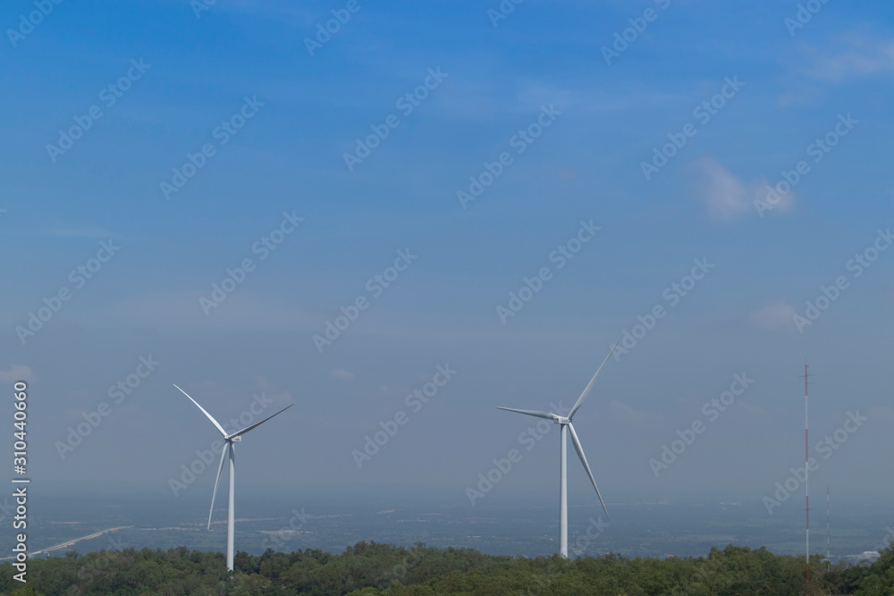 Mountain wind turbines for generating electricity Behind the mountains in the sky there are white clouds on a sunny and foggy day. Mountain wind turbines for generating electricity Behind the mountains in the sky there are white clouds on a sunny and foggy day.