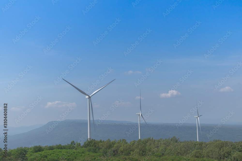 Wind turbine for electricity generation Behind the mountains in the sky there are white clouds on a sunny and foggy day. Wind turbine for electricity generation Behind the mountains in the sky there are white clouds on a sunny and foggy day.