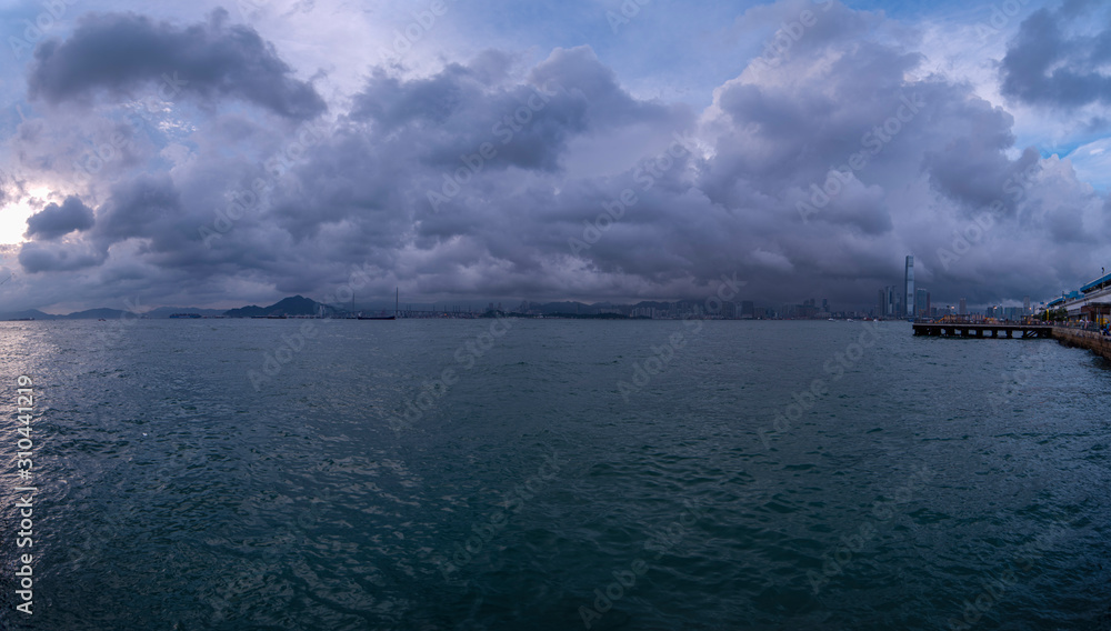 a merged panorama of victoria harbour and the upcoming storm above in hong kong, china