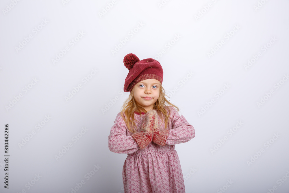 cute happy little girl in mittens, gloves and a winter hat on a white background 