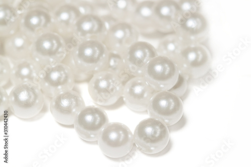 Necklace with shining white pearl lie in a bunch form isolated background macro