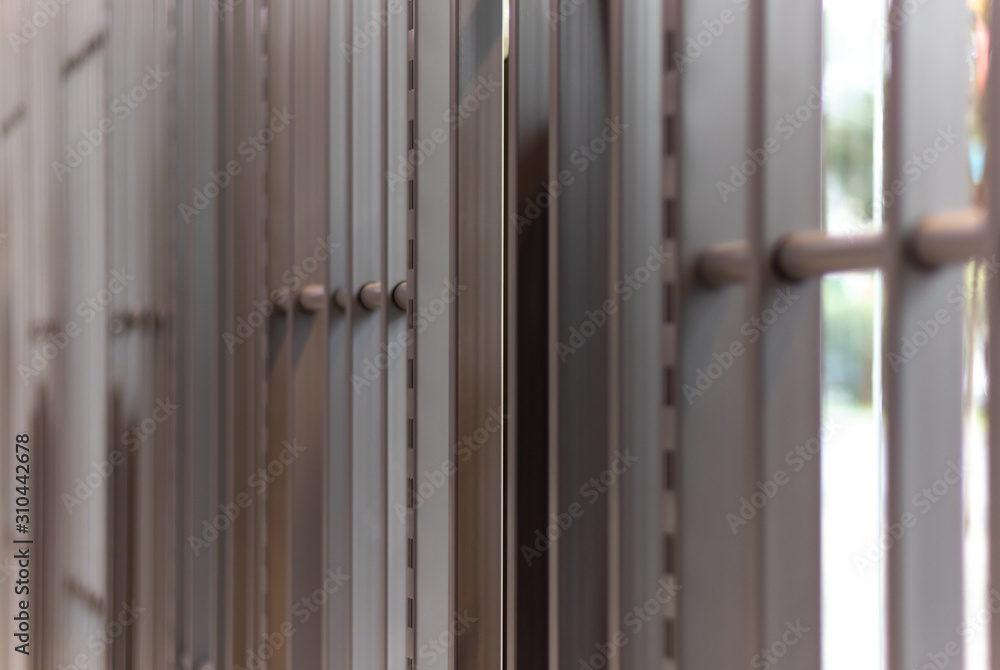 iron bars, metal grating or prison cell, bright blurred outdoor background