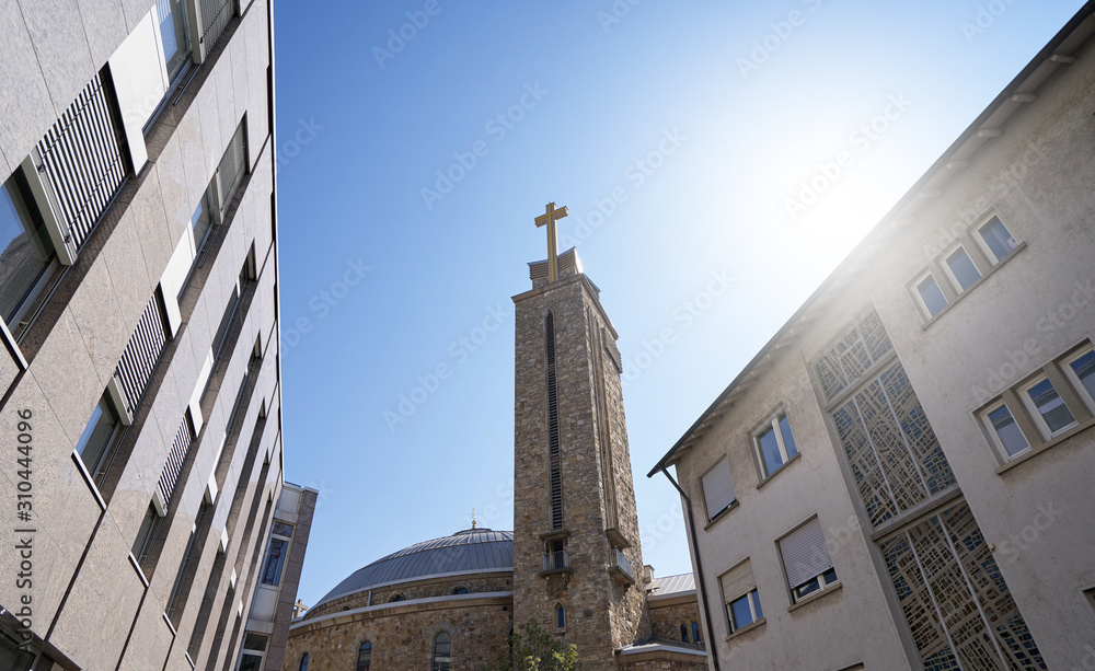 Tower with a cross of the church The heart of Jesus between residential buildings in the European city of Pforzheim, Germany, on a sunny day. Space for text