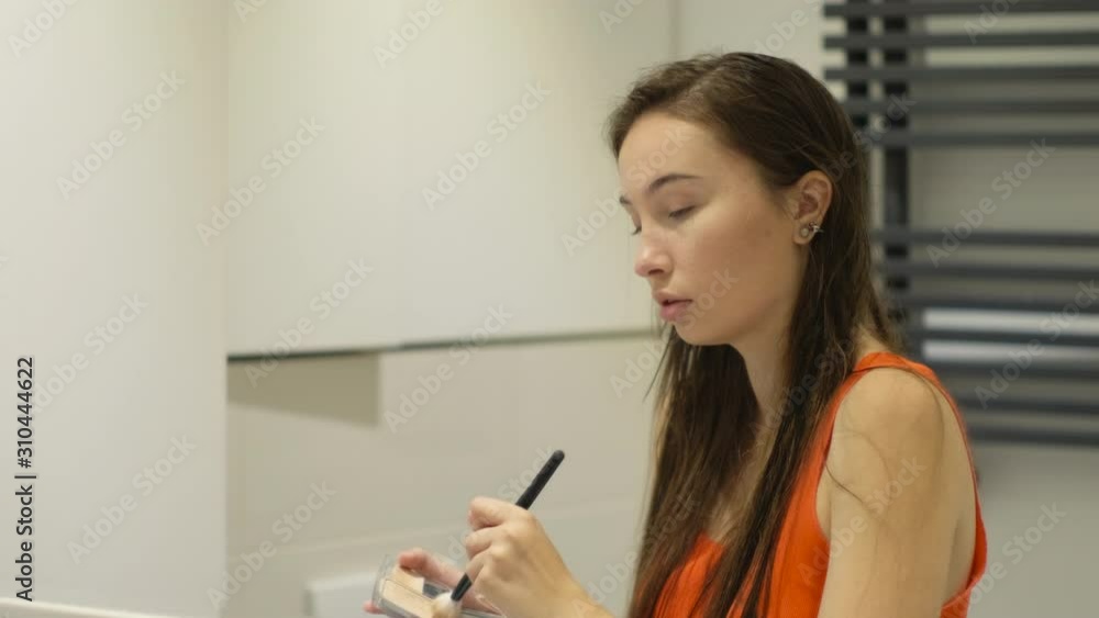woman is applying cosmetic powder on her face by brush woman is applying cosmetic powder on her face by brush