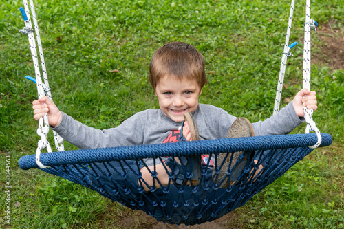 Little boy enyoing time in park lying in a swing photo