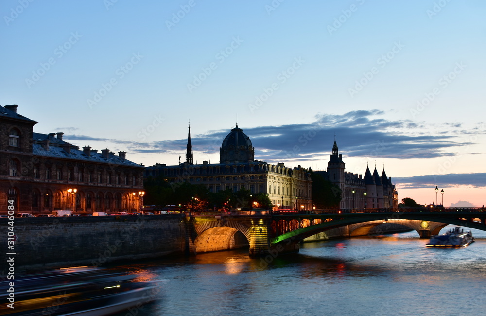La Conciergerie and the Sainte Chapelle spire from Seine River bridge at sunset. Paris, France.