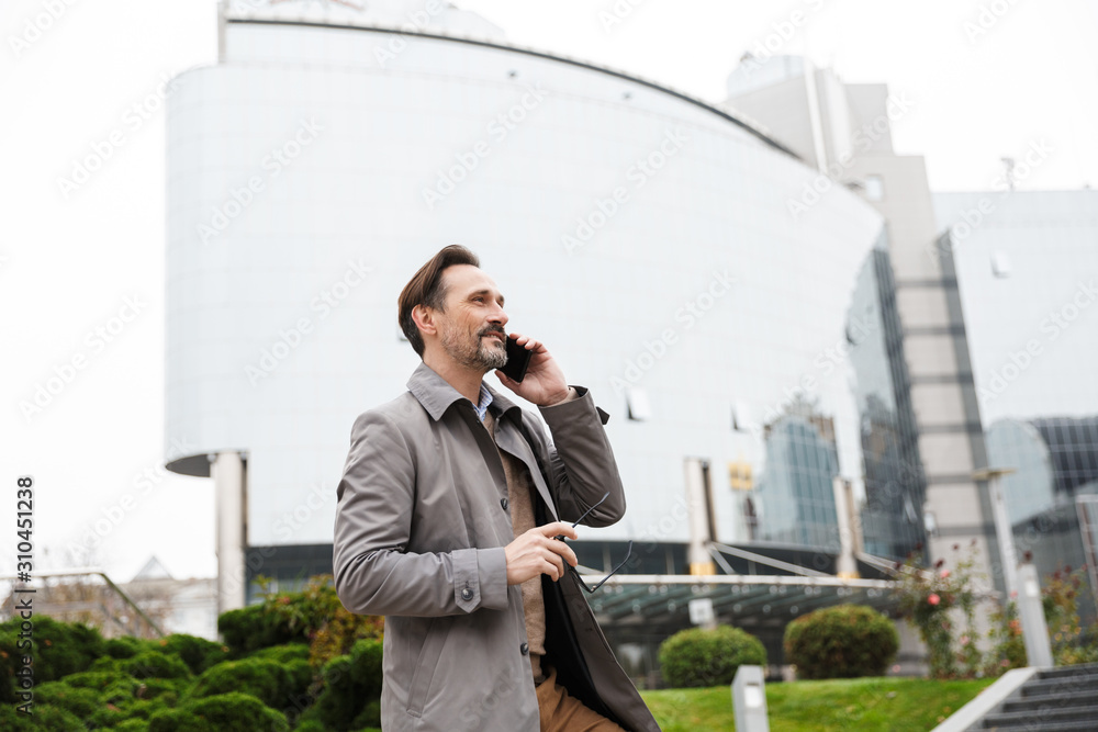 Image of handsome smiling businessman talking on cellphone Image of handsome smiling businessman talking on cellphone