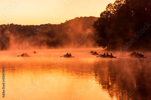 Silhouette of the rafting boat in the golden misty lake under the warm morning sunlight in Pang Ung © sittitap