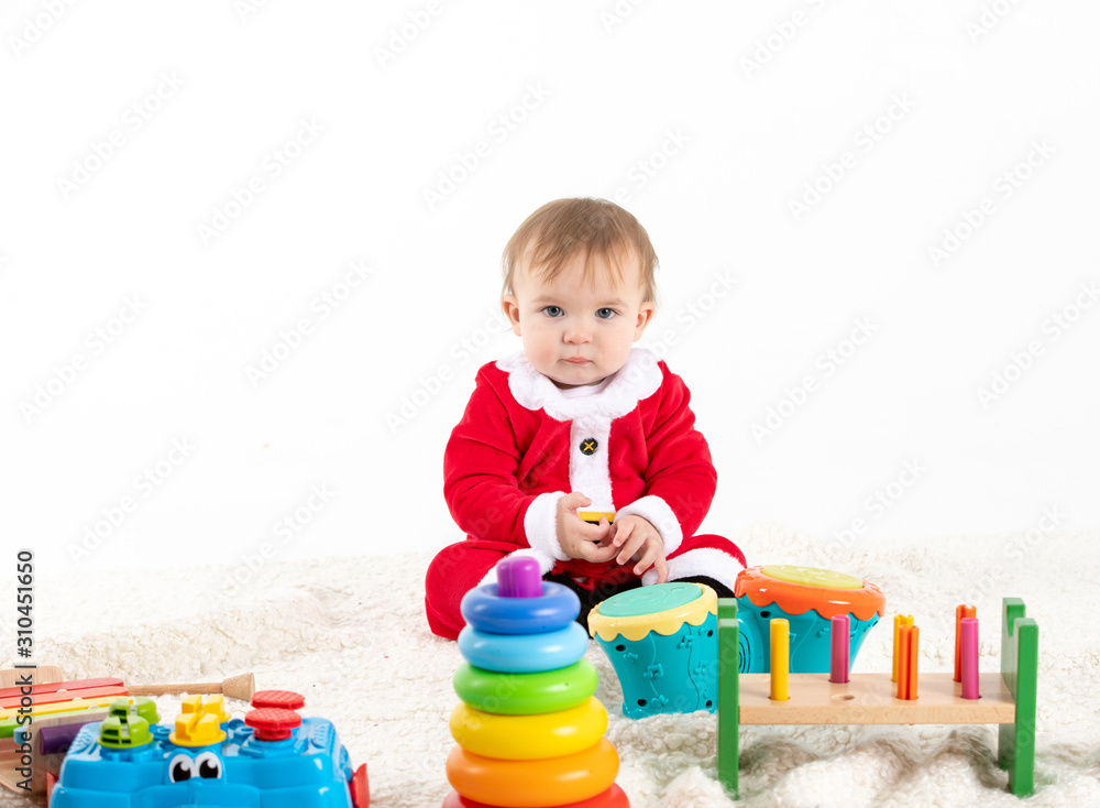Baby disguised as santa claus surrounded by toys Baby disguised as santa claus surrounded by toys