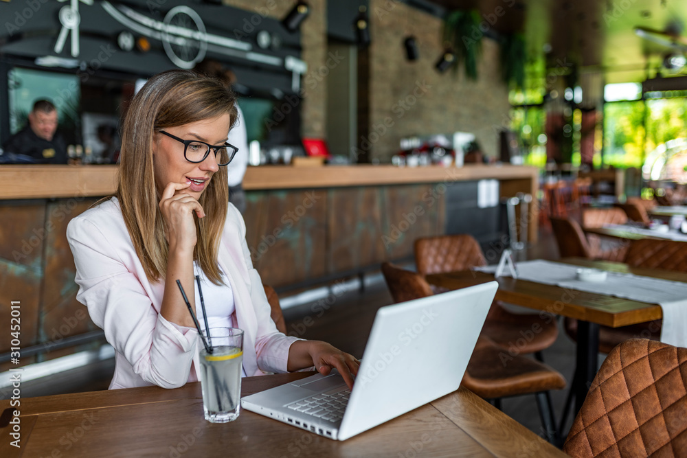 Beautiful brunette using notebook in cafe. Busy female student preparing for exam in cafe. Pretty woman is working in a café. Young woman typing on laptop in cafe Beautiful brunette using notebook in cafe. Busy female student preparing for exam in cafe. Pretty woman is working in a café. Young woman typing on laptop in cafe