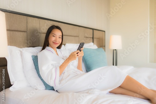 Portrait beautiful young asian women using mobile smart phone with coffee cup on bed