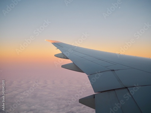 wing of an airplane flying above clouds Airplane wing is flying above cloudscape in early morning with golden sunrise with copyspace concept time to journey