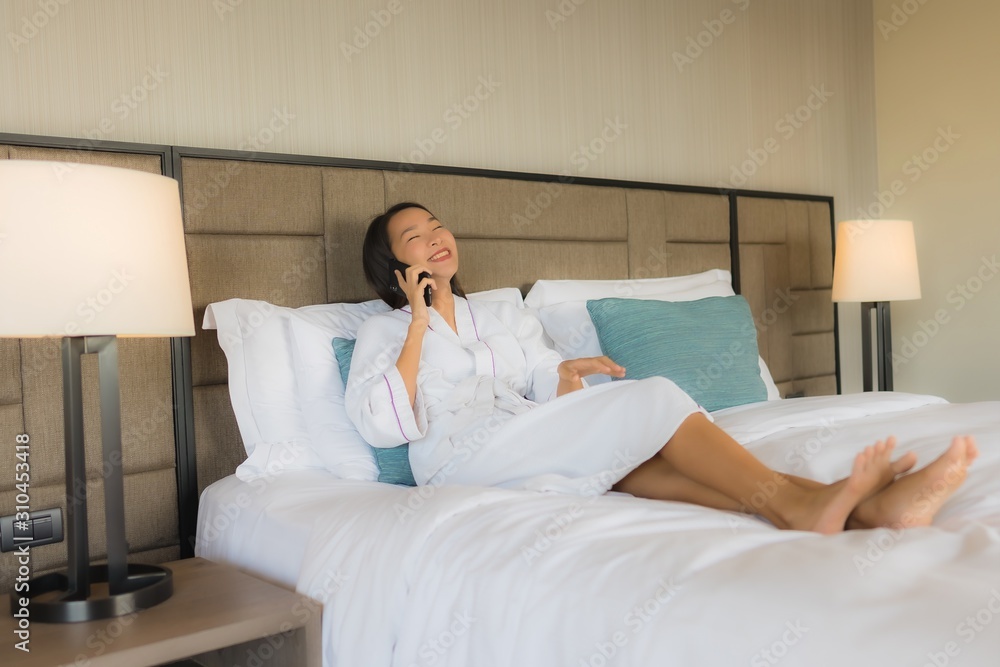 Portrait beautiful young asian women using mobile smart phone with coffee cup on bed Portrait beautiful young asian women using mobile smart phone with coffee cup on bed