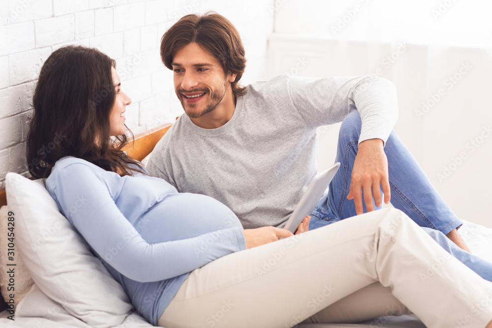 Expecting couple using digital tablet together at home