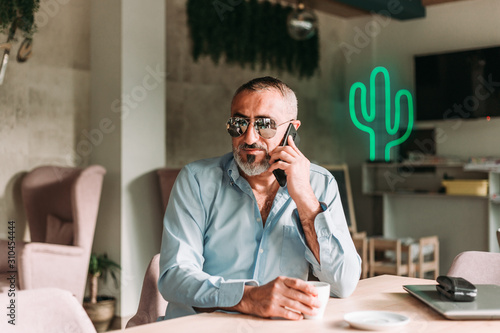 Portrait of middle age man with beard and with eyeglasses talking on the phone