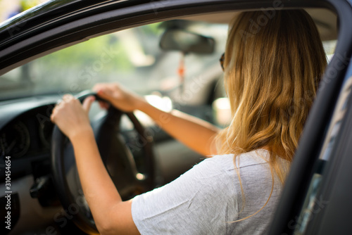 Young beautiful blonde hair girl with driving a car. Confident and beautiful. Rear view of attractive young woman in casual wear looking forward her while driving a car. © Dominika