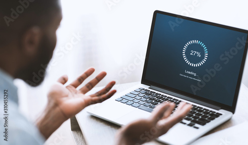 Foto Worried african american man looking at laptop with loading screen
