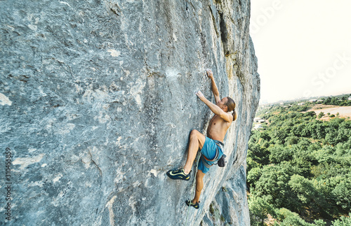muscular man rockclimber with naked torso climbing on tough sport route. outdoors rock climbing and active lifestyle concept, climbing moments