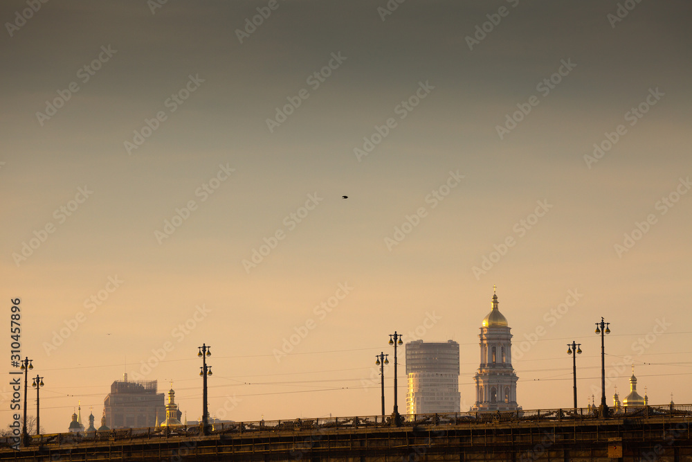 View of the big city over bridge in awesome bright sunset. Domes of cathedrals and churches of the Kiev-Pechersk Lavra. Kyiv. Ukraine.