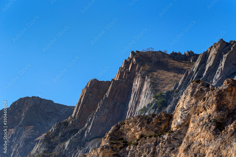 Rocks and dry grass in North Caucasus mountains in autumn on sunny day