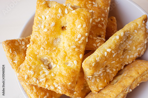 Freshly prepared puff pastry with sesame seeds close-up in a white plate. Details. Home baking concept. photo