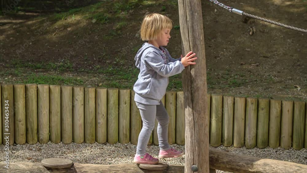 A young girl playing on a playground, walking along a wood and practicing her balance, her grandma comes to help in the end A young girl playing on a playground, walking along a wood and practicing her balance, her grandma comes to help in the end