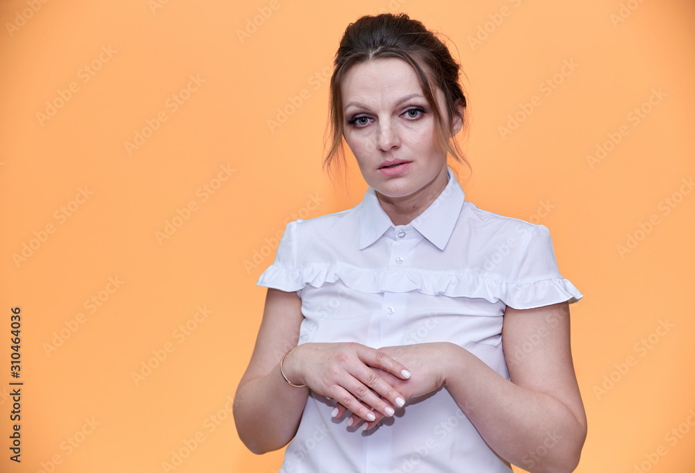 Obraz premium Business concept. Close-up portrait of an adult pretty woman of 40 years old with good makeup in a business suit on a yellow background. Standing right in front of the camera with a smile.
