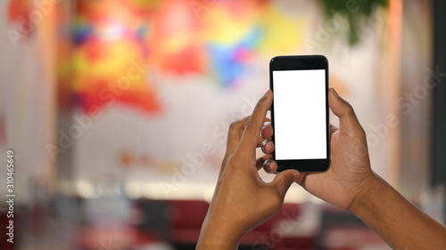 Man's hands holding smartphone with empty screen and bokeh on festival blurred background.