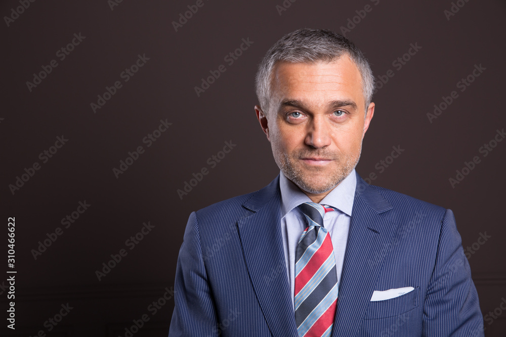 A portrait of a man on a matte brown wall in the background. A businessman. A portrait of a man on a matte brown wall in the background. A businessman.