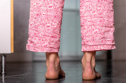 Woman is standing on the tile with bare feet
