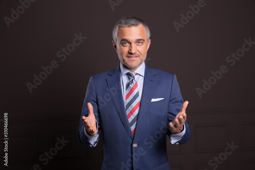 A portrait of a man on a matte brown wall in the background. A businessman.