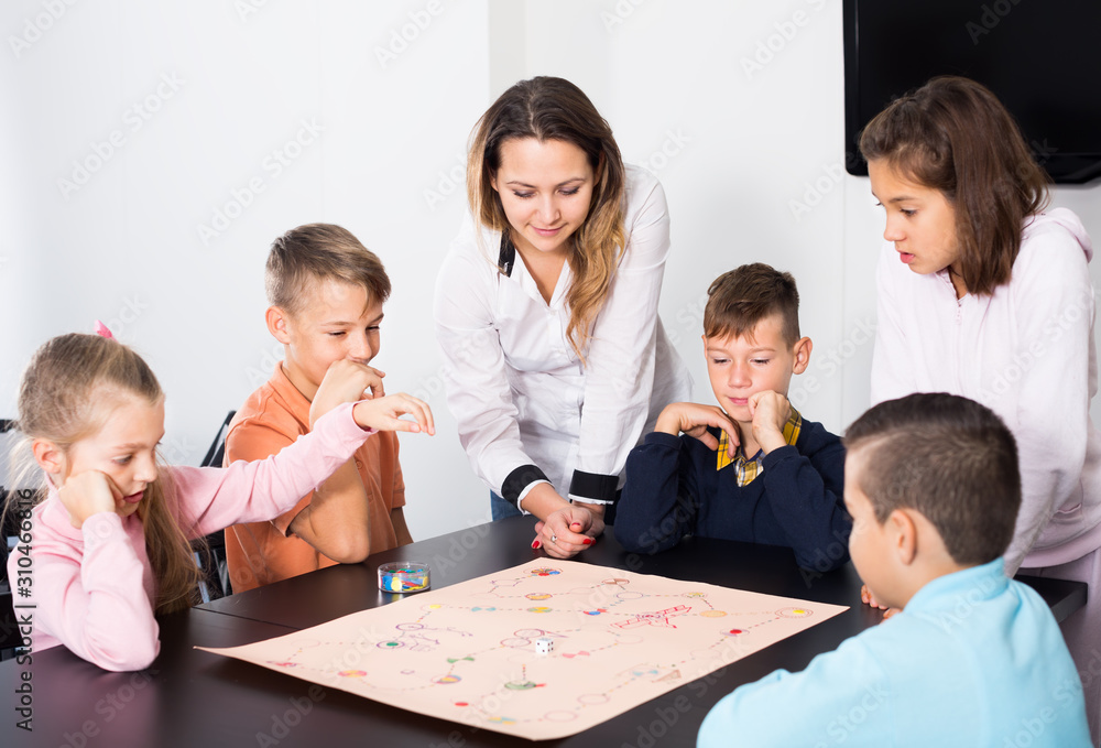 Fototapeta premium Elementary age friendly children at table with board game and dice