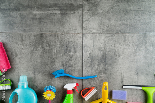 House cleaning concept. Top view of colorful cleaning products on gray tile floor.