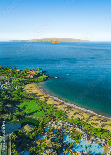 Vertical, portrait orientation drone picture showing the beautiful coast line and beaches of Wailea, Maui, Hawaii. Molokini can be seen in the distance. A crescent shaped volcanoe island. photo