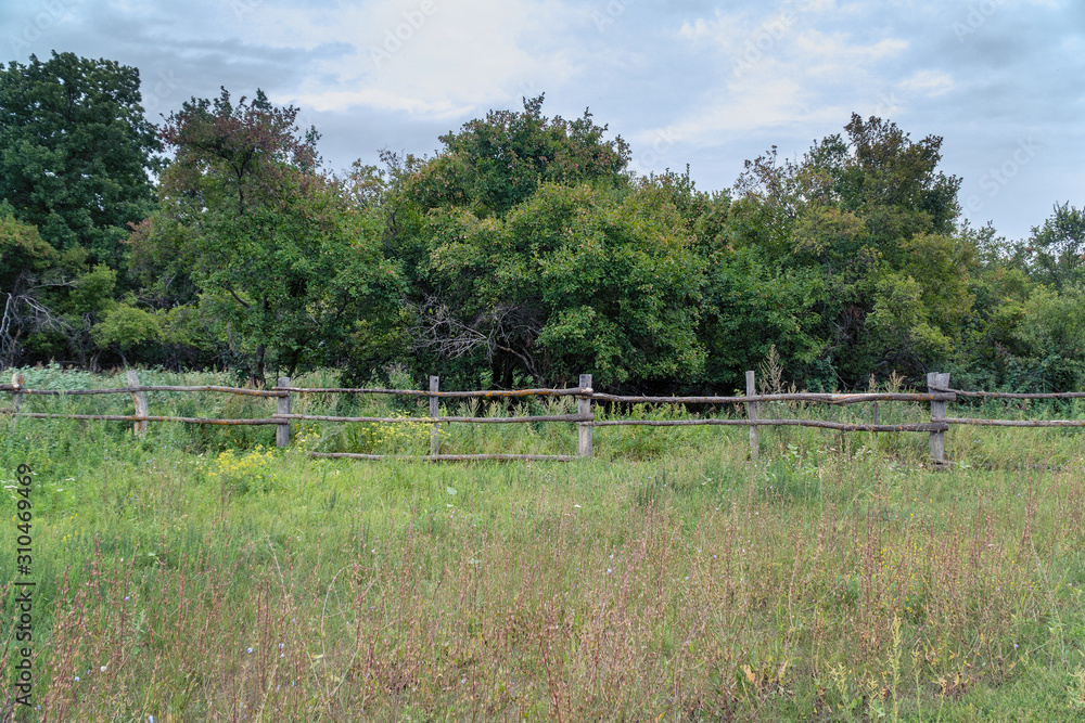 Primitive rustic wooden fence in front of forest Primitive rustic wooden fence in front of forest