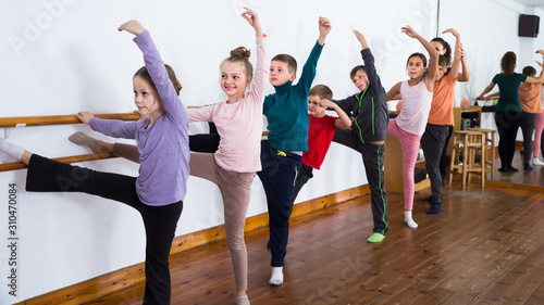friendly children rehearsing ballet dance in studio