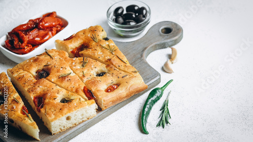 Traditional Italian Focaccia with tomatoes, olives and rosemary - homemade flat bread focaccia.