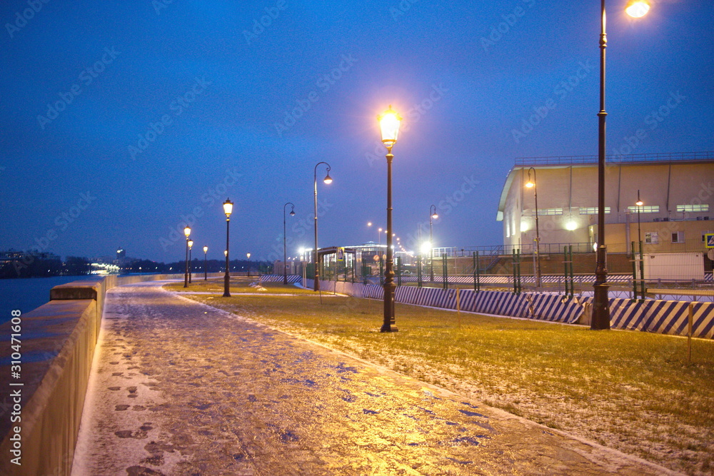 promenade with lanterns on a dark winter evening