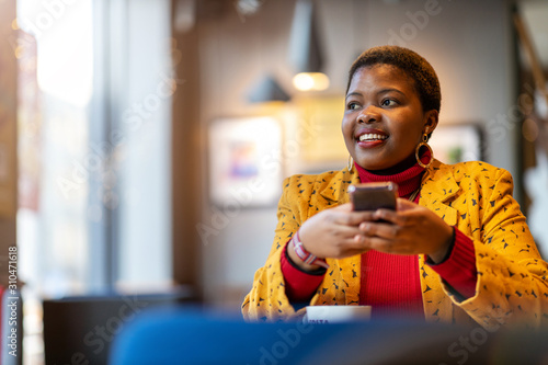Happy young woman with smartphone in a cafe