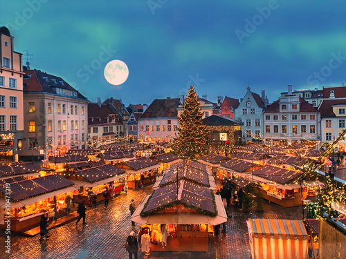 Christmas tree in Tallinn old town hall square without snow ,moon on blue sky ,best in Europe Christmas  market place kiosk ,holiday travel to Europe travel agency   medieval city blurred decoration  photo